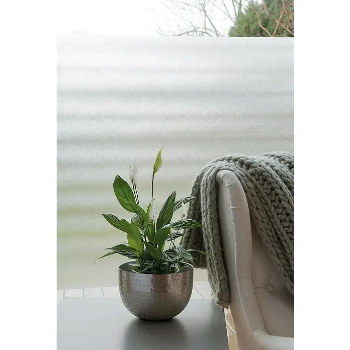 D-c-fix Static Premium Glasfolie Meterware Sofelto - Breite: 45 cm, Transluzent, Statisch haftend - Ein silberner Topf mit einer grünen Pflanze steht auf einem Tisch vor einem Fenster mit einer Decke daneben.