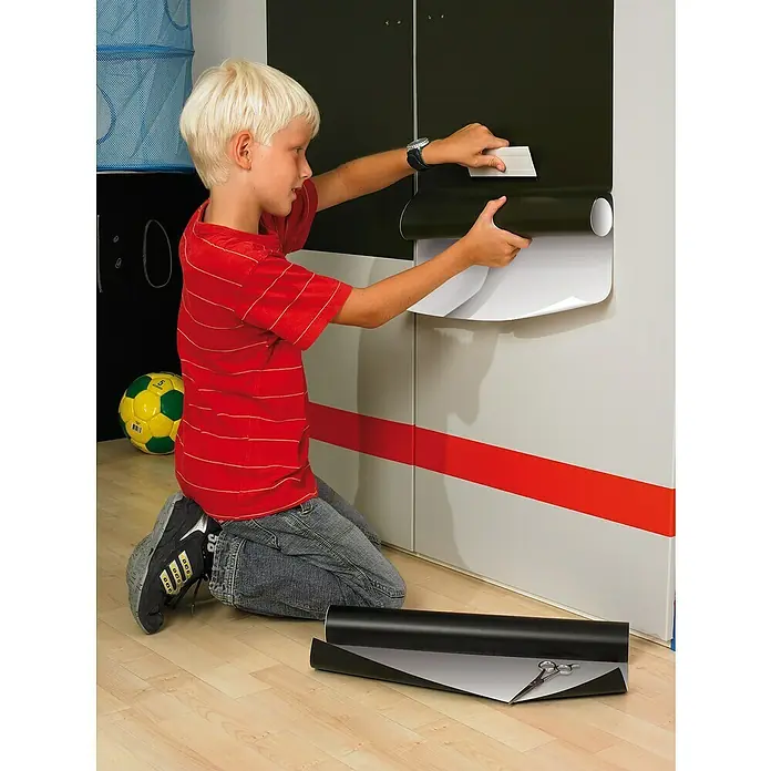 D-c-fix Tafelfolie - 150 x 90 cm, Tafelgrün, Selbstklebend - Ein Kind bringt eine selbstklebende Möbelfolie an einem Schrank an, um das Erscheinungsbild des Möbelstücks zu verändern.