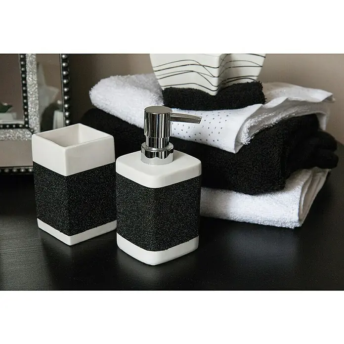 D-c-fix Metalleffektfolie Metallic Glitter - 200 x 67,5 cm, Schwarz/Glitzer, Selbstklebend - Nahaufnahme von einem quadratischen, weißen, mit schwarzen Glitzer verziertem Seifenspender und Zahnbürstenhalter auf einem Tisch.