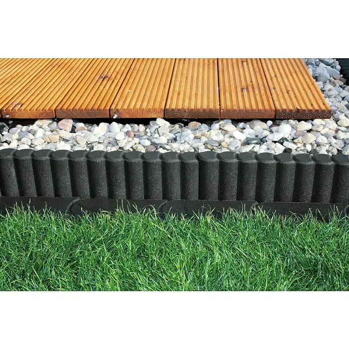 Christoph Palisaden-Randstein - Anthrazit, 50 x 6 x 15 cm, Beton - Eine Nahaufnahme einer stilvollen Gartengestaltung mit einem Holzdeck, Zierkies, einer schwarzen Beetumrandung und saftigem Gras.