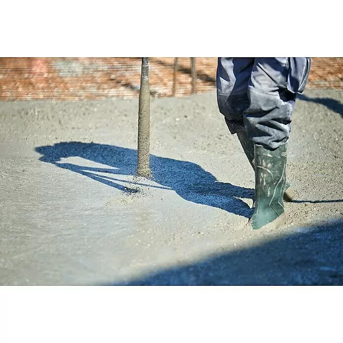 Berg Betonrüttler TBR 2000 - 2.000 W, 4.000 U/min - Arbeiter in grünen Stiefeln benutzt Betonrüttler in nassem Beton beim Bau.