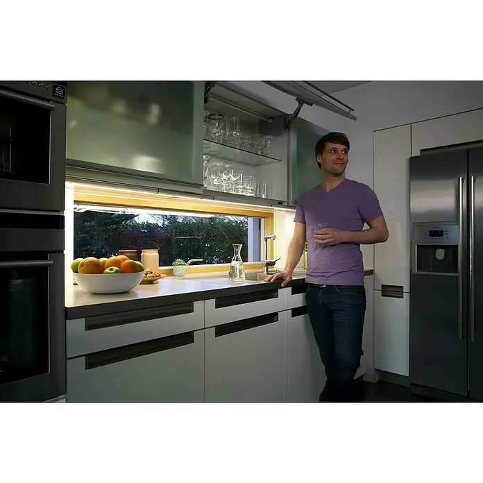 Osram Lámpara LED bajo mueble LED Flat - 12 W, Largo: 52,7 cm, Blanco neutro - Hombre en una cocina moderna con líneas elegantes, materiales de alta calidad y un enfoque en el diseño minimalista con encimera.