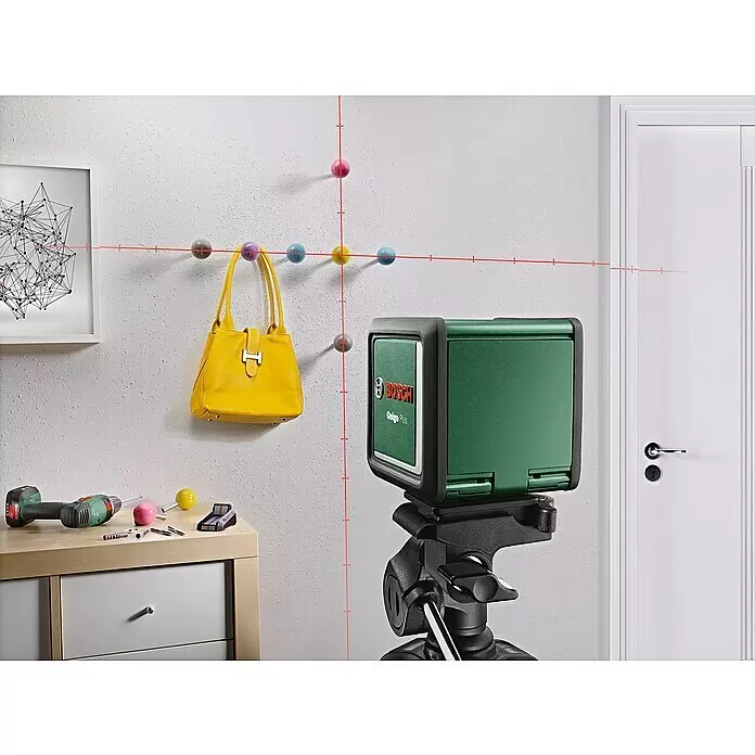 Bosch Kreuzlinienlaser Quigo Plus - Max. Arbeitsbereich: 7 m - Grünes Bosch Quigo Plus Kreuzlinienlaser auf Stativ, projiziert rote Horizontal- und Vertikallinien zur präzisen Ausrichtung.