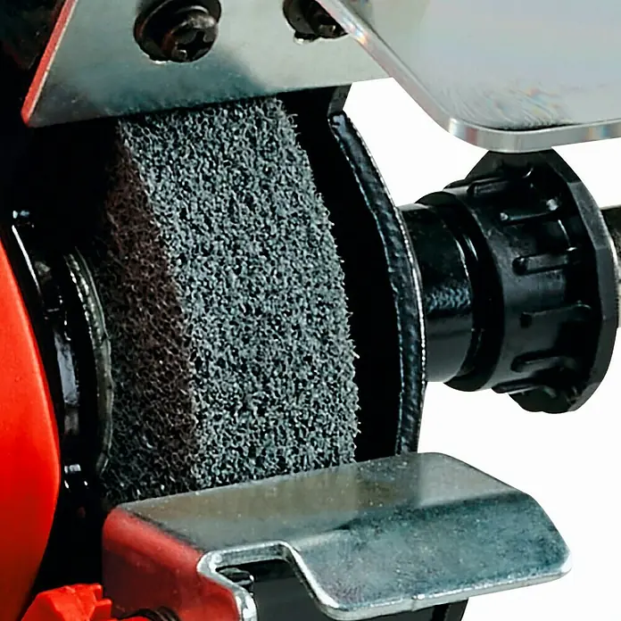 Einhell Esmeriladora doble eléctrica TC-XG 75 Kit - 150 W, 9.900 r.p.m. - Primer plano de una amoladora de banco con una muela abrasiva. La amoladora es roja y negra y la muela es gris.