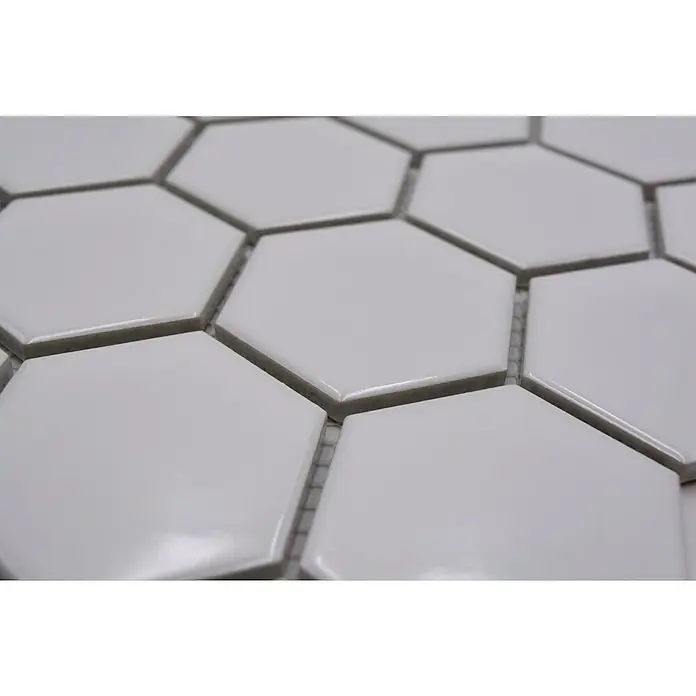 Mosaikfliese Hexagon Uni HX 080 - 32,5 x 28,1 cm, Weiß, Glänzend - Nahaufnahme von weißen Sechseckfliesen, die ein modernes und sauberes Design für Küchen oder Badezimmer zeigen. Die glänzende Oberfläche reflektiert das Licht.
