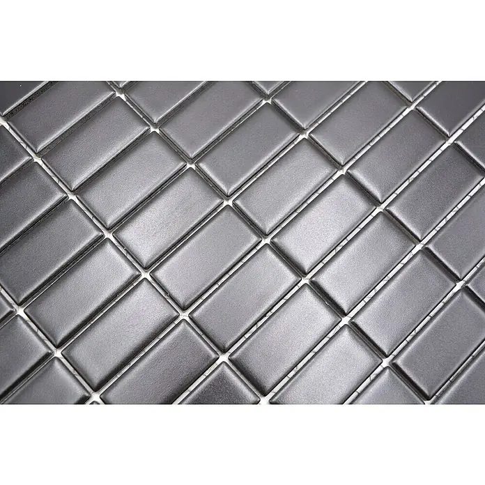 Mosaikfliese Stäbchen Uni ST 395 - 29,8 x 29,8 cm, Schwarz, Matt - Nahaufnahme von glänzenden, anthrazitfarbenen rechteckigen Fliesen, die diagonal in einem Fischgrätenmuster angeordnet sind. Perfekt für moderne Wand- und Bodenbeläge.