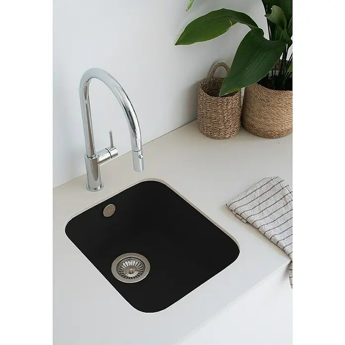 Poalgi Fregadero encastrable Gandía Soft 35 - 44,5 x 38 cm, Material compuesto, Negro, Brillante - Primer plano de un fregadero de cocina moderno con cubeta negra y elegante grifo cromado, complementado con cestas decorativas y un paño de cocina a rayas.