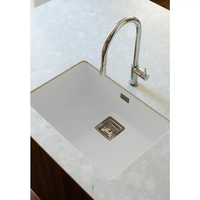 Poalgi Fregadero encastrable Zie Soft 60 - 45 x 65 cm, Material compuesto, Blanco, Brillante - Primer plano de un fregadero de cocina blanco moderno con grifo cromado, incrustado en una encimera con aspecto de mármol.