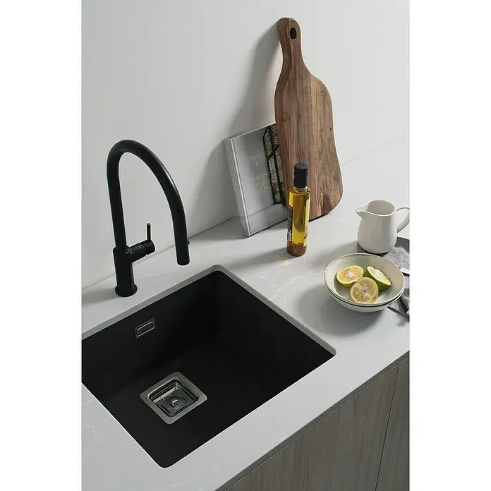 Poalgi Fregadero encastrable Zie Soft 45 - 45 x 50 cm, Material compuesto, Negro, Brillante - Primer plano de un fregadero de cocina negro con grifo, tabla de cortar y limones sobre una encimera brillante.