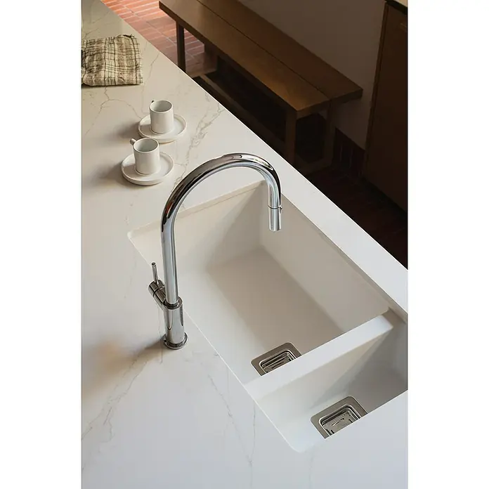 Poalgi Fregadero encastrable Zie Soft 70 - 45 x 75 cm, Material compuesto, Número de cubetas: 1,5 ud., Blanco, Brillante - Primer plano de un fregadero de cocina moderno con grifo cromado sobre una encimera de mármol blanco, con paño y tazas.