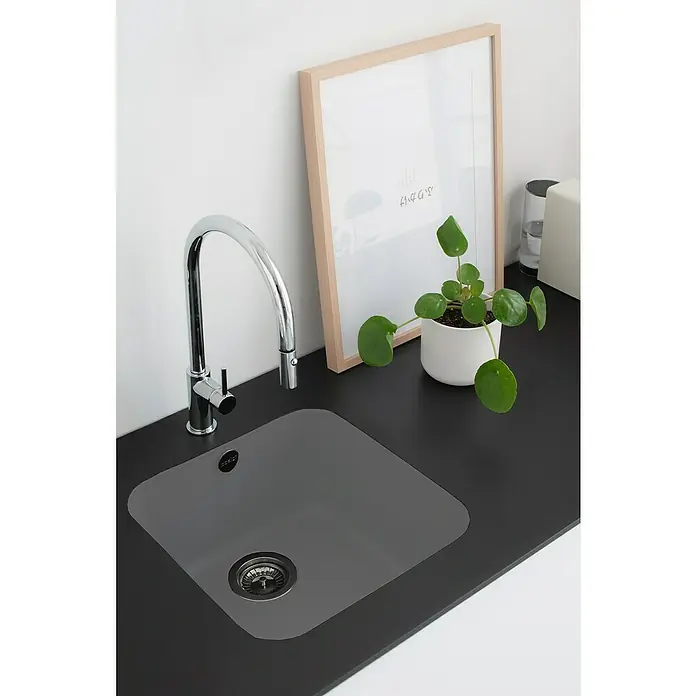 Poalgi Fregadero encastrable Gandía Soft 40 - 44,5 x 44 cm, Material compuesto, Concret, Brillante - Un moderno fregadero de cocina con un elegante grifo cromado, una planta de interior y un marco de madera clara sobre una encimera oscura.