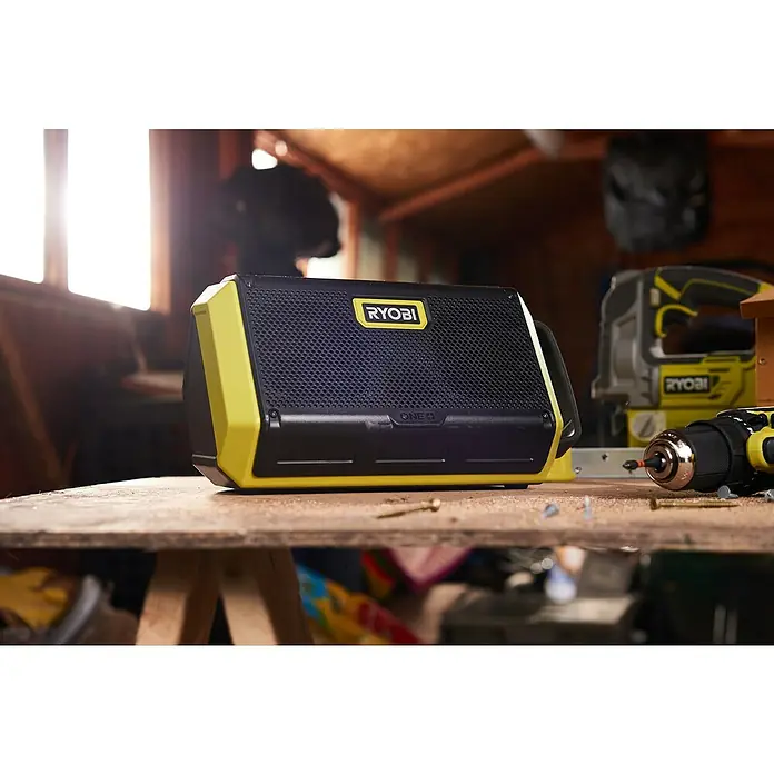 Ryobi ONE+ Altavoz Bluetooth RBT18-0 - 18 V, Sin batería, Potencia de salida altavoz: 15 W - Un altavoz Ryobi se encuentra en un banco de trabajo en un primer plano. Ryobi es una marca de herramientas eléctricas.