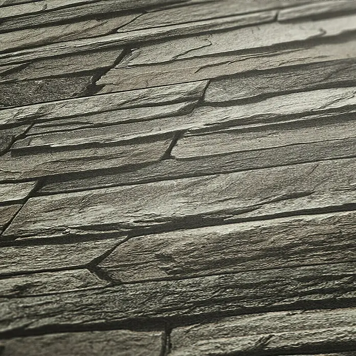 A.S. Création Elements Vliestapete Bruchsteinmauer - Grau/Creme, Steinoptik, 10,05 x 0,53 m - Nahaufnahme einer grauen Schieferwand mit unregelmäßigen Steinen, die eine rustikale und natürliche Textur erzeugen.