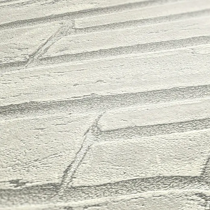 A.S. Création Elements Vliestapete Steine IV - Weiß/Grau, Steinoptik, 10,05 x 0,53 m - Nahaufnahme einer weißen Ziegelwandtapete mit einer fühlbaren Textur, die eine rustikale und schlichte Optik bietet.
