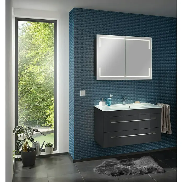 Camargue Stella LED-Spiegelschrank - B x H: 100 x 73,7 cm, Holz, Grafit, Mit Beleuchtung, Kantenausführung Tür: Eckig - Ein modernes Badezimmer mit einem grauen Waschtisch mit Schubladen und einem beleuchteten Spiegelschrank an einer blau gemusterten Wand.