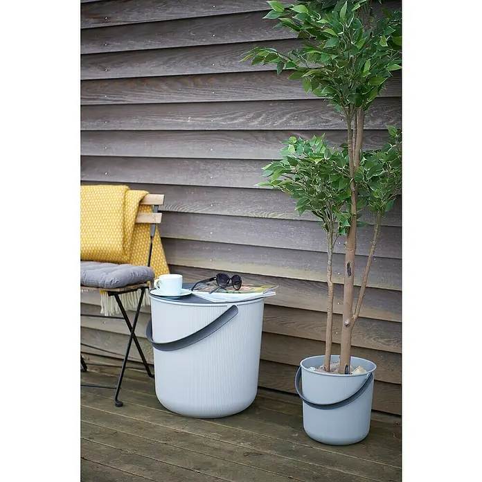 Eimer Akita - L x B x H: 277 x 271 x 258 mm, 10 l, Grau - Ein grauer Outdoor-Beistelltisch in Eimerform mit Griff und passendem Pflanzenkübel auf einer Holzterrasse.