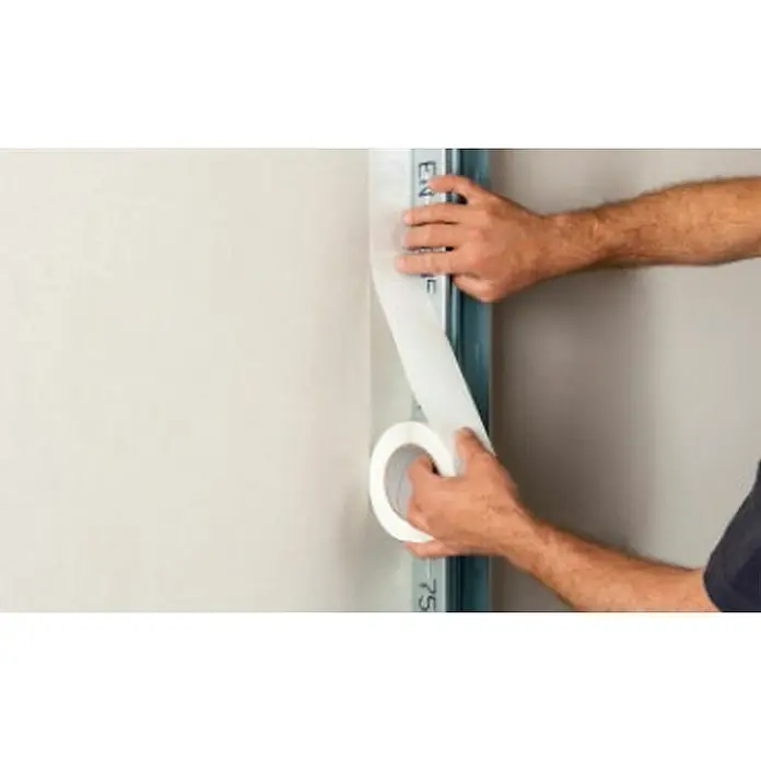 Probau Abschlussband Trennfix50 m x 65 mm - Ein Mann befestigt mit Klebeband eine Metallschiene an einer Wand, um eine saubere Kante für Bauarbeiten zu schaffen, während er das Klebeband abrollt.