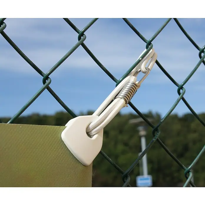 Clips Holdon Midi - 4 Stk., Weiß - Nahaufnahme eines Spannfix-Gummiseils mit Kunststofföse zur Bannerbefestigung an einem grünen Maschendrahtzaun bei blauem Himmel.