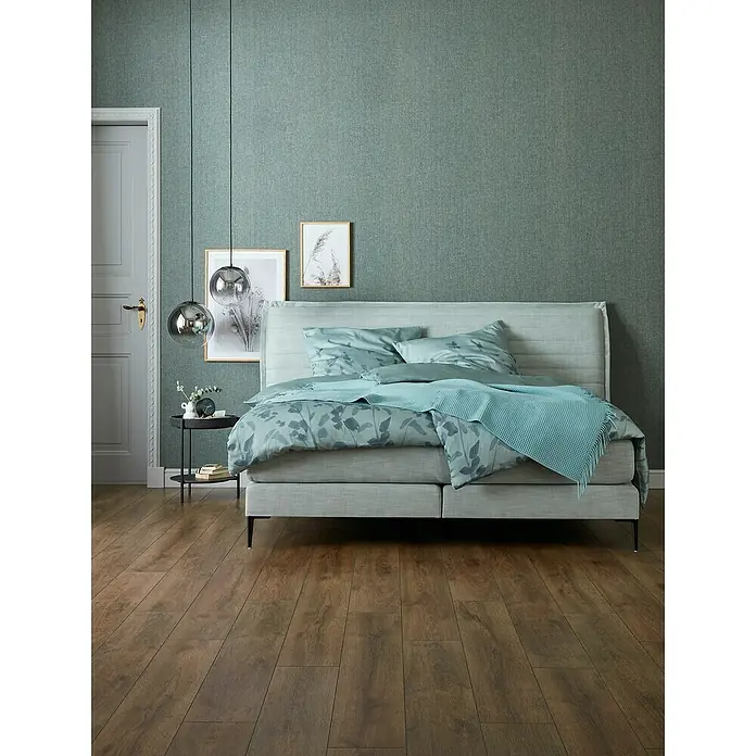 SCHÖNER WOHNEN-Kollektion Vliestapete Unistruktur - Grün/Grau, Uni, 10,05 x 0,53 m - Einladendes Schlafzimmer mit einem komfortablen Doppelbett, stilvollen Pendelleuchten und warmen Holzböden für eine entspannte Atmosphäre.
