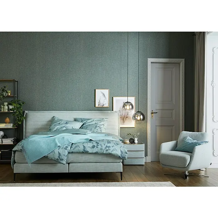 SCHÖNER WOHNEN-Kollektion Vliestapete Unistruktur - Grün/Grau, Uni, 10,05 x 0,53 m - Einladendes Schlafzimmer mit Boxspringbett, Nachttisch, Sesseln und stilvoller Dekoration in sanften Farben für eine ruhige Atmosphäre.