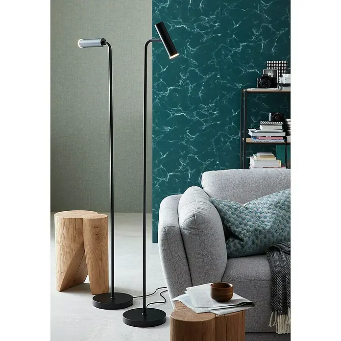 SCHÖNER WOHNEN-Kollektion Vliestapete Marmoroptik - Grün/Grau, Steinoptik, 10,05 x 0,53 m - Elegantes Wohnzimmer mit zwei Stehlampen, einem grauen Sofa und einem Holzhocker als Beistelltisch. Die Lampen spenden gezieltes Licht.