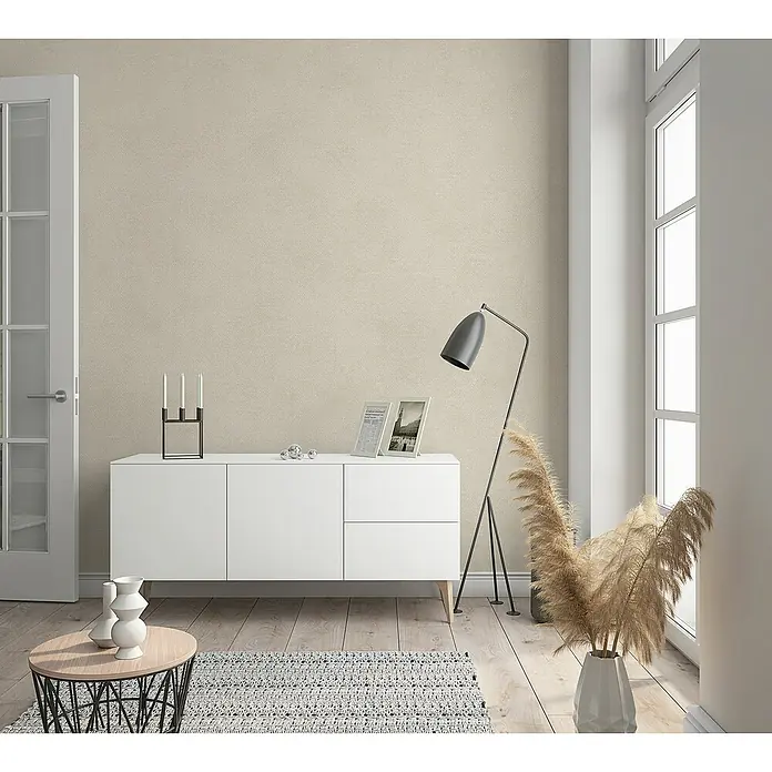 Marburg Sand & Stones Vliestapete Shades - Beige, Uni, 10,05 x 0,53 m - Ein modernes Wohnzimmer mit einem weißen Sideboard, einer Stehlampe und dekorativen Elementen, die eine stilvolle Atmosphäre schaffen.