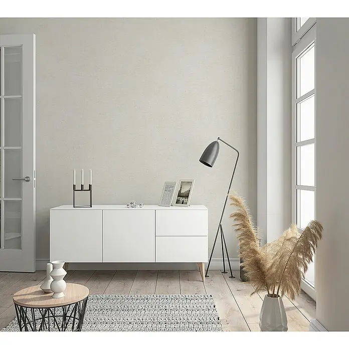 Marburg Sand & Stones Vliestapete Shades - Greige, Uni, 10,05 x 0,53 m - Ein modernes Wohnzimmer mit einem weißen Sideboard, einer Stehlampe und dekorativen Elementen, die eine gemütliche Atmosphäre schaffen.
