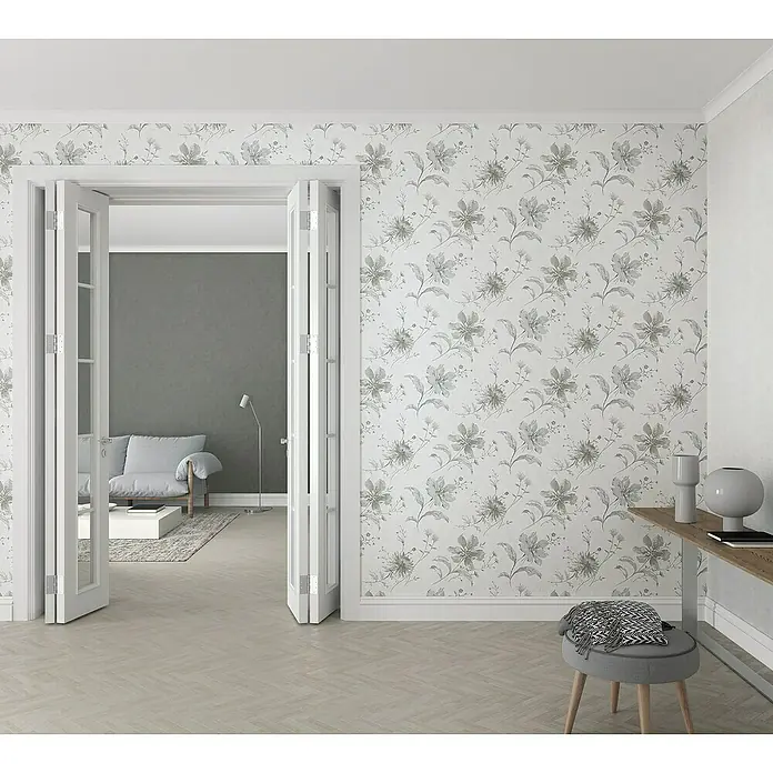 Marburg Sand & Stones Vliestapete Shades - Dunkelgrau, Uni, 10,05 x 0,53 m - Zimmer mit floral gemusterter Tapete, Flügeltüren zum Wohnzimmer und modernen Möbeln, die eine elegante und komfortable Atmosphäre schaffen.