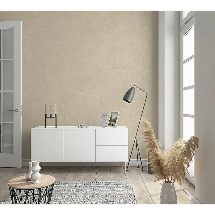 Marburg Sand & Stones Vliestapete Shades - Cremebeige, Uni, 10,05 x 0,53 m - Ein modernes Wohnzimmer mit einem weißen Sideboard, einer Stehlampe und dekorativen Elementen, die eine gemütliche Atmosphäre schaffen.