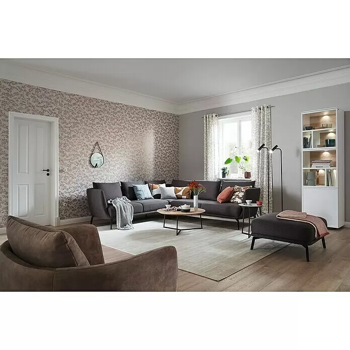 SCHÖNER WOHNEN-Kollektion New Spirit Vliestapete Blüten-Allover - Grau/Gold, Floral, 10,05 x 0,53 m - Gemütliches Wohnzimmer mit dunkelgrauem Ecksofa, braunem Sessel, Couchtisch und weißer Vitrine, die einen modernen, einladenden Raum schaffen.