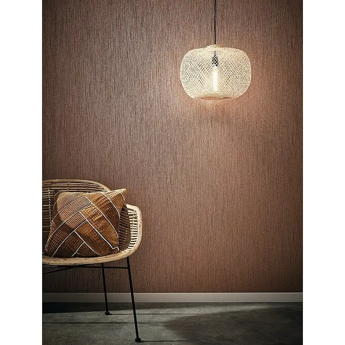 Marburg Sand & Stones Vliestapete Dune I - Braun, Uni, 10,05 x 0,53 m - Nahaufnahme eines dekorierten Innenraums mit einem Rattansessel, einem Kissen und einer gewebten Pendelleuchte.