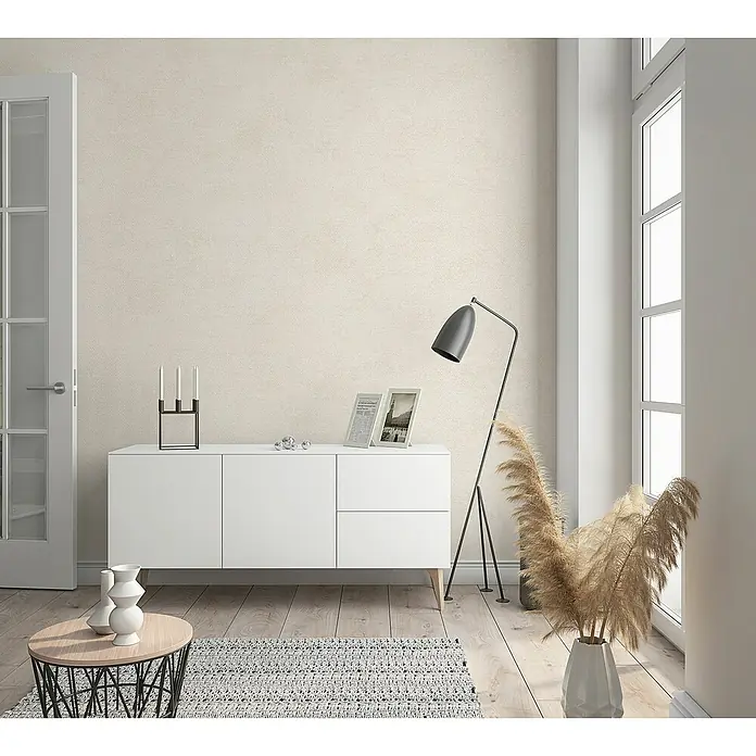 Marburg Sand & Stones Vliestapete Shades - Creme, Uni, 10,05 x 0,53 m - Ein stilvolles Wohnzimmer mit einem weißen Sideboard, einem modernen Lampendesign und dekorativen Elementen.