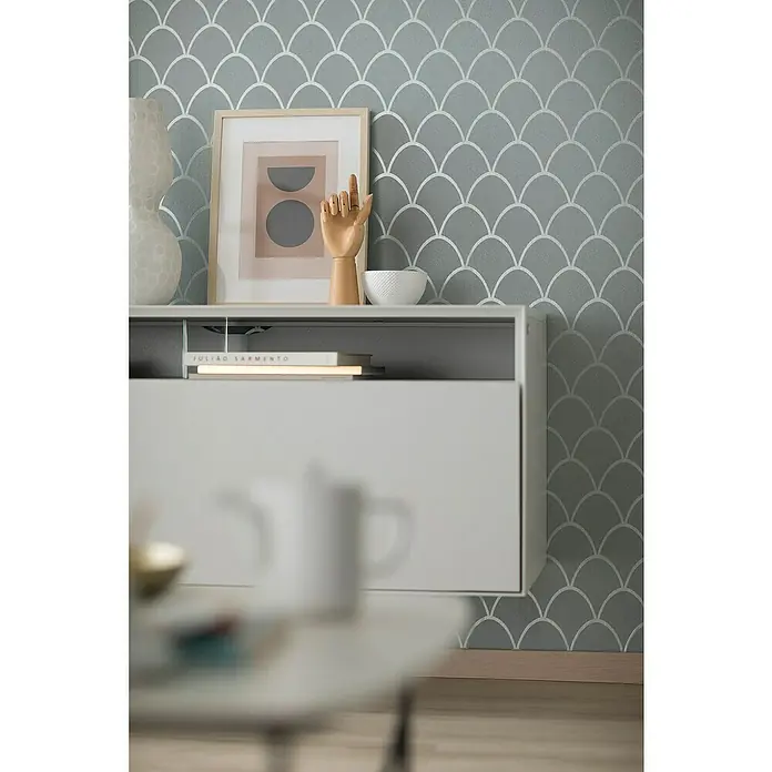 SCHÖNER WOHNEN-Kollektion New Spirit Vliestapete - Grün, Grafisch, 10,05 x 0,53 m - Nahaufnahme eines stilvollen weißen Sideboards mit Deko-Elementen und einem attraktiven, grau gemusterten Hintergrund.