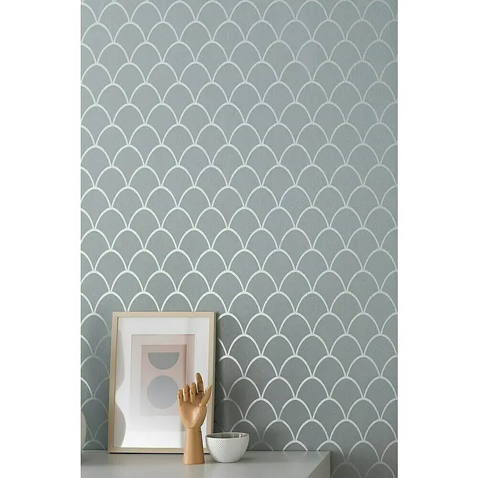 SCHÖNER WOHNEN-Kollektion New Spirit Vliestapete - Grün, Grafisch, 10,05 x 0,53 m - Nahaufnahme einer grauen Wand mit einem sich wiederholenden silbernen Fischschuppenmuster, das eine moderne und elegante Ästhetik erzeugt.