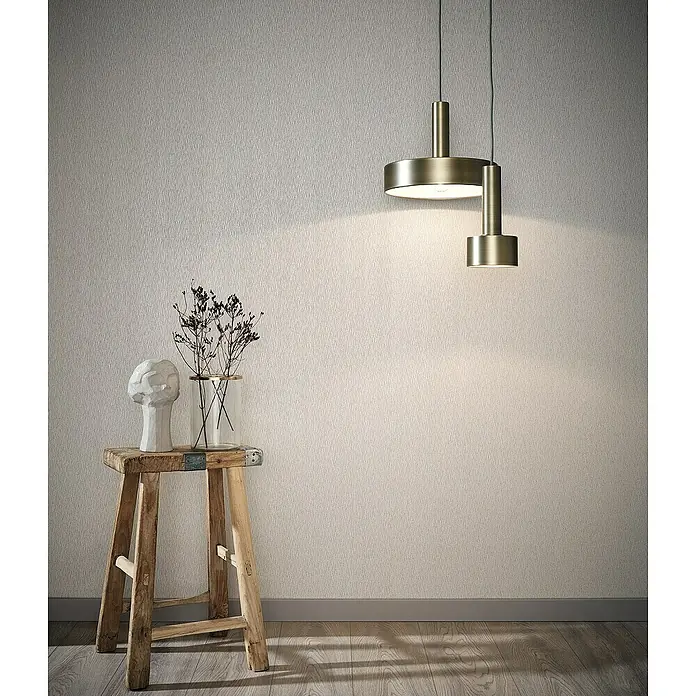 Marburg Sand & Stones Vliestapete Dune I - Beige, Uni, 10,05 x 0,53 m - Elegante Messing Pendelleuchte im Interieur, die ein warmes Licht auf einen Hocker mit Dekorationen wirft. Stilvolles Design für modernes Ambiente.