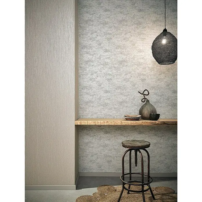 Marburg Sand & Stones Vliestapete Dune I - Hellbeige, Uni, 10,05 x 0,53 m - Eine moderne Inneneinrichtung mit stilvoller Barhocker und dekorativen Elementen unter einer hängenden Lampe.