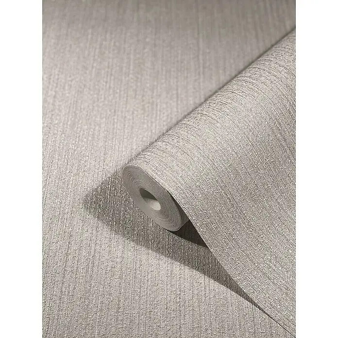 SCHÖNER WOHNEN-Kollektion New Spirit Vliestapete Struktur - Lichtgrau, Uni, 10,05 x 0,53 m - Ein Rolle beiger Tapete mit subtiler Textur liegt auf einer ebenen Fläche und wirft einen Schatten. Ideal für die Wandgestaltung.