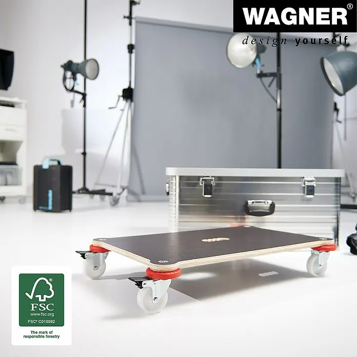 Wagner System Transportroller Protection MM 1375 - L x B x H: 710 x 440 x 123 mm, Traglast: 200 kg, Holz - Das Bild zeigt ein Rollbrett mit roten Rollen und einer schwarzen Platte, das für den Transport von Gegenständen konzipiert ist. Im Hintergrund befindet sich eine Alubox.