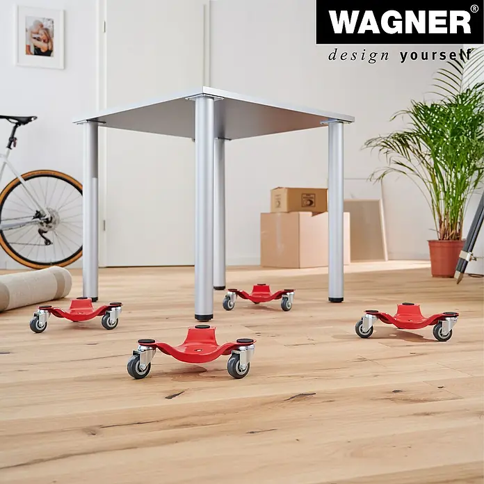Wagner System Transportroller MM 1196 - L x B x H: 250 x 250 x 75 mm, Traglast: 100 kg, Stahl - Das Bild zeigt einen silbernen Tisch mit vier roten Rollbrettern unter den Beinen, die das Verschieben des Tisches erleichtern.