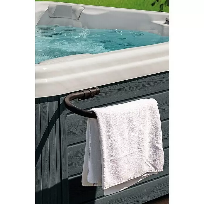Camargue Whirlpool-Handtuchhalter - 41 x 24 cm, Grau - Gebogener dunkler Metall-Handtuchhalter für Whirlpools mit einem weißen Handtuch. Er ist am dunklen Whirlpoolgehäuse neben sprudelndem Wasser befestigt.