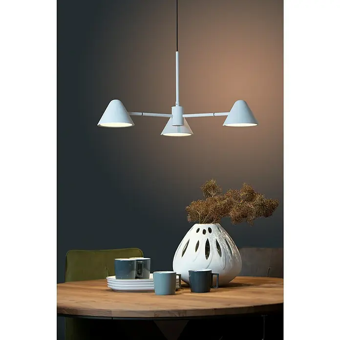 Lucide Devon LED-Pendelleuchte - Höhe: 65 cm, Weiß - Elegante, moderne weiße Pendelleuchte mit drei konischen Lampenschirmen über einem runden Holztisch mit Dekorationsgegenständen.