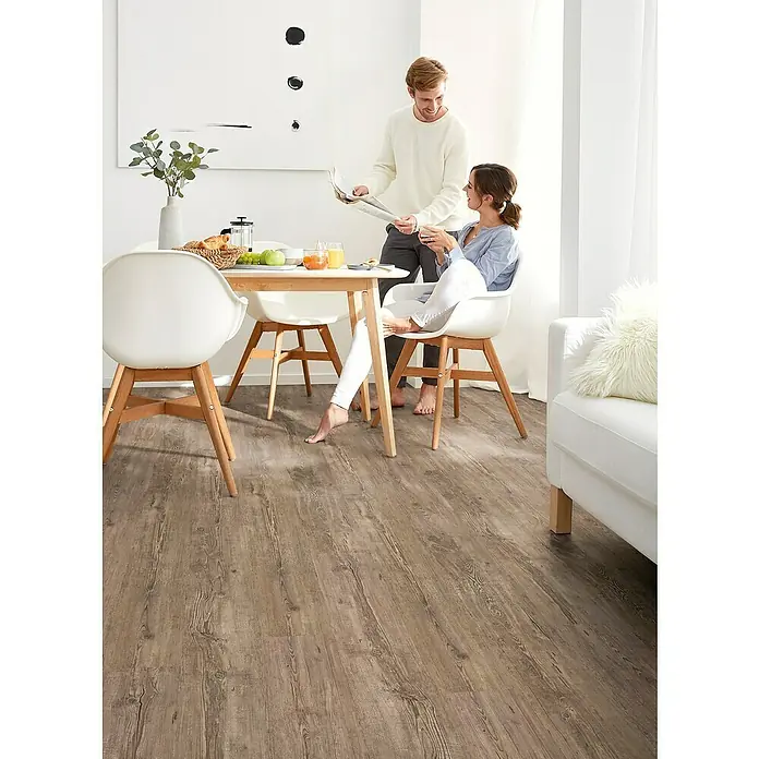 Decolife Vinylboden Comfort - Tuscan Pine, Landhausdiele, 1.220 x 185 x 10,5 mm - Ein Paar genießt den Morgen auf einem braunen Holzboden. Der Holzboden verleiht dem Raum eine warme und einladende Atmosphäre.