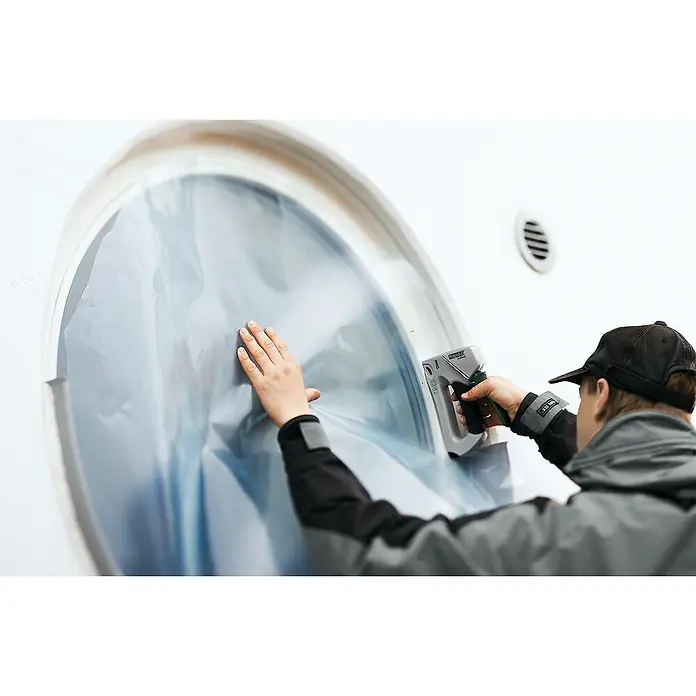 Rapid Handtacker ALU840 - Klammertiefe: 6 mm - 14 mm, Geeignet für: Flachdrahtklammern Nr. 140 - Ein Arbeiter befestigt eine Folie mit einem Rapid Akku-Tacker an einem Fenster, um es zu schützen.
