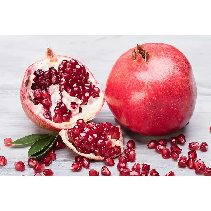 Granado - Punica granatum - Primer plano de granadas frescas que destaca las vibrantes semillas rojas y la textura de la fruta.