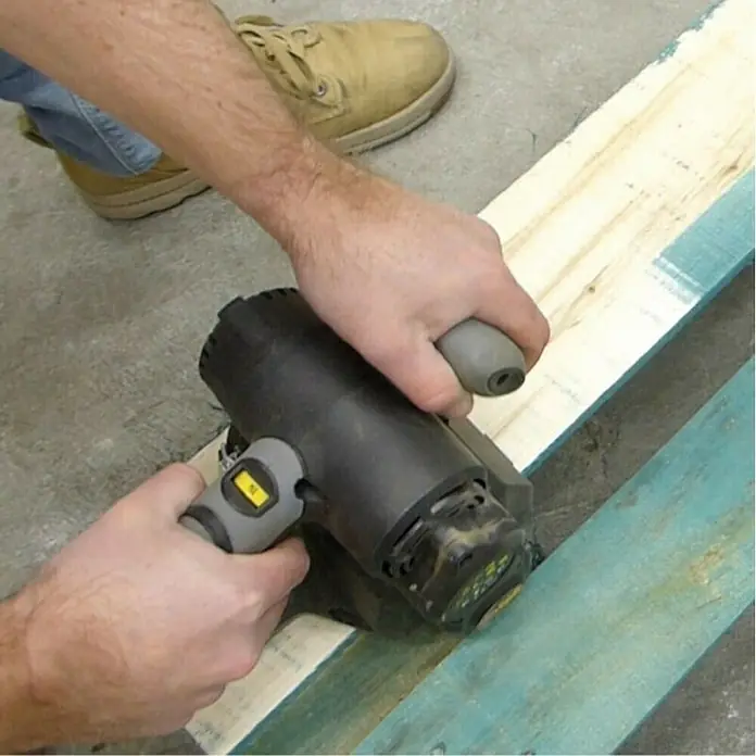 Fartools Desbastadora Renovator REX 80 Compact - 420 W - La lijadora eléctrica negra se utiliza para alisar una pieza de madera. Un trabajador está usando la lijadora para lijar una pieza de madera.