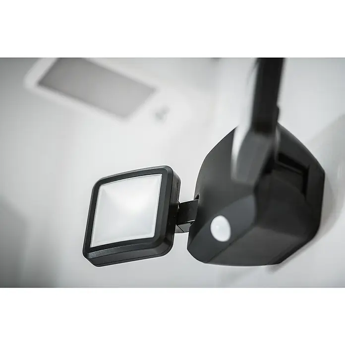 Ledvance LED-Sensor-Außenwandstrahler Double10 W, Schwarz, Bewegungsmelder - Nahaufnahme einer schwarzen LED-Sicherheitsleuchte mit Bewegungssensor an einer weißen Wand, die modernes Design und Funktionalität vereint.