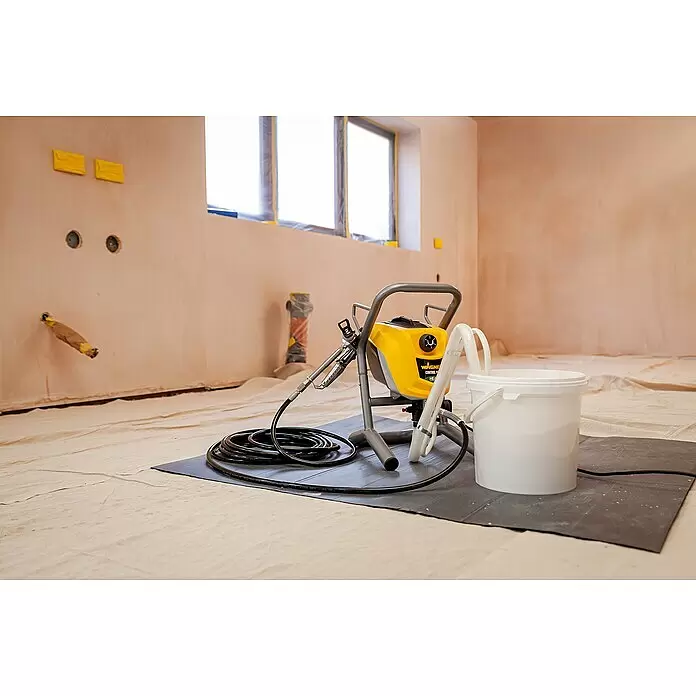 Wagner High Efficiency Airless Farbsprühsystem Control Pro 250 M - 550 W, Förderleistung: 1,25 l/min - Gelbe und graue Wagner Farbspritzmaschine mit schwarzen Schläuchen und einem weißen Eimer, in einem Raum zum Streichen bereit.