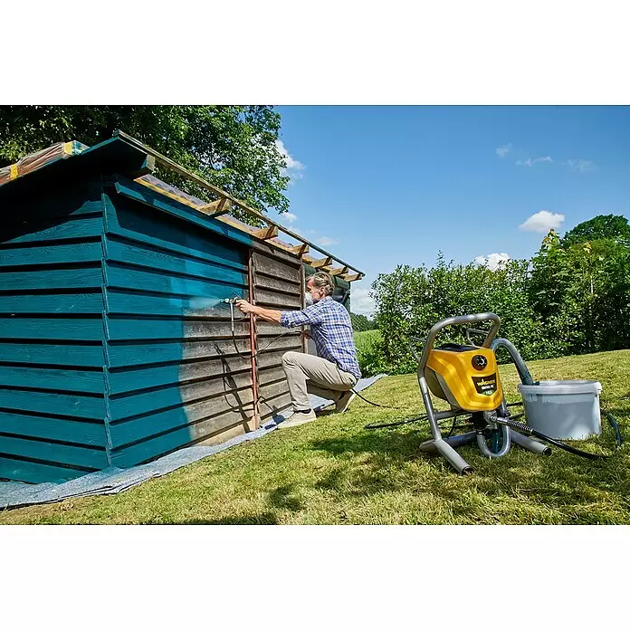 Wagner High Efficiency Airless Farbsprühsystem Control Pro 250 M - 550 W, Förderleistung: 1,25 l/min - Gelbe und graue Wagner Control Pro HEA Farbspritzanlage im Einsatz beim Streichen eines Holzschuppens.
