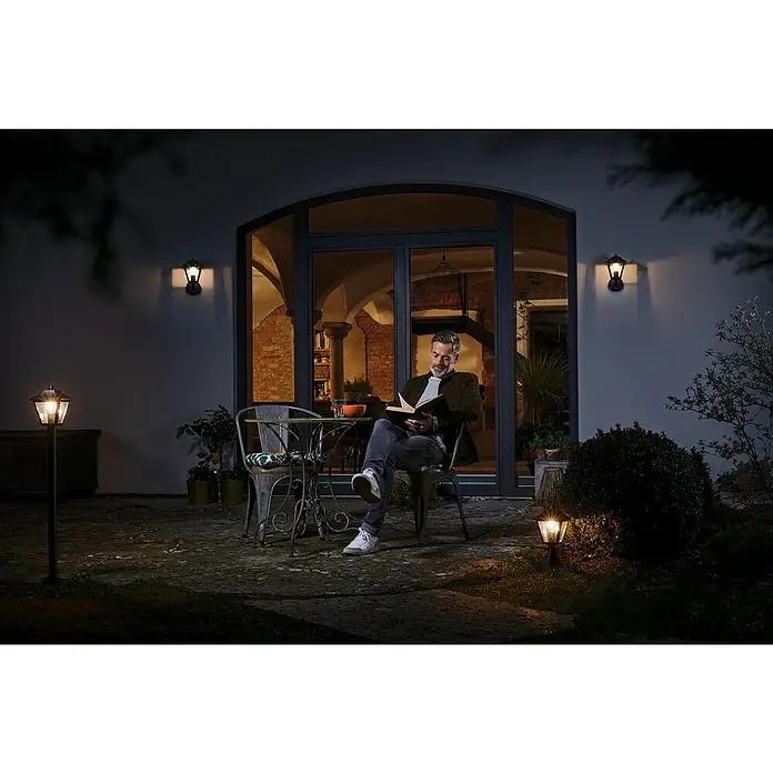 Osram Endura Classic Außenwandleuchte Tradition - Hängend, 23 x 17 x 23 cm, Schwarz, IP44 - Ein Mann liest auf seiner Terrasse im Licht von Außenleuchten. Die Gartenleuchten sorgen für eine gemütliche Atmosphäre am Abend.