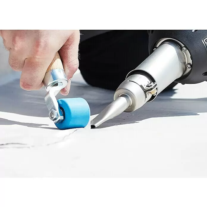 Leister Andruckrolle - Breite: 28 mm - Eine Person verschweißt mit einem Heißluftgerät und einer blauen Rolle eine weiße Membran. Die Werkzeuge werden an einer Naht angewendet.